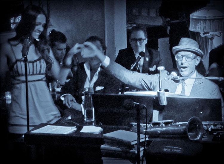 Alyssa singing at a jazz club with Jeff Goldblum on piano