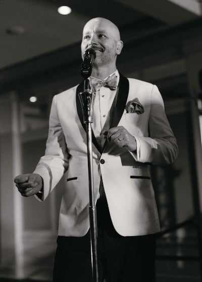 Rick singing in a white tuxedo jacket